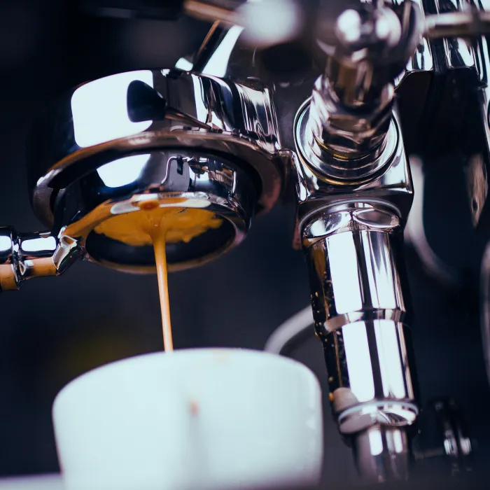Frischer Kaffee läuft aus einer Kaffee-Maschine. Der Barista ist zuständig dafür.