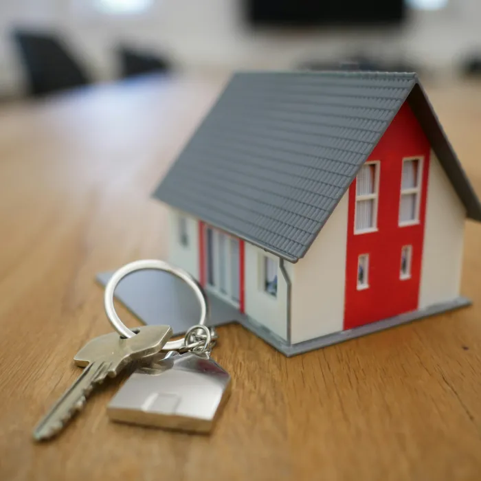 Ein kleines schönes Haus als Schlüsselanhänger an einem Schlüssel symbolisiert Immobilienvermarktung